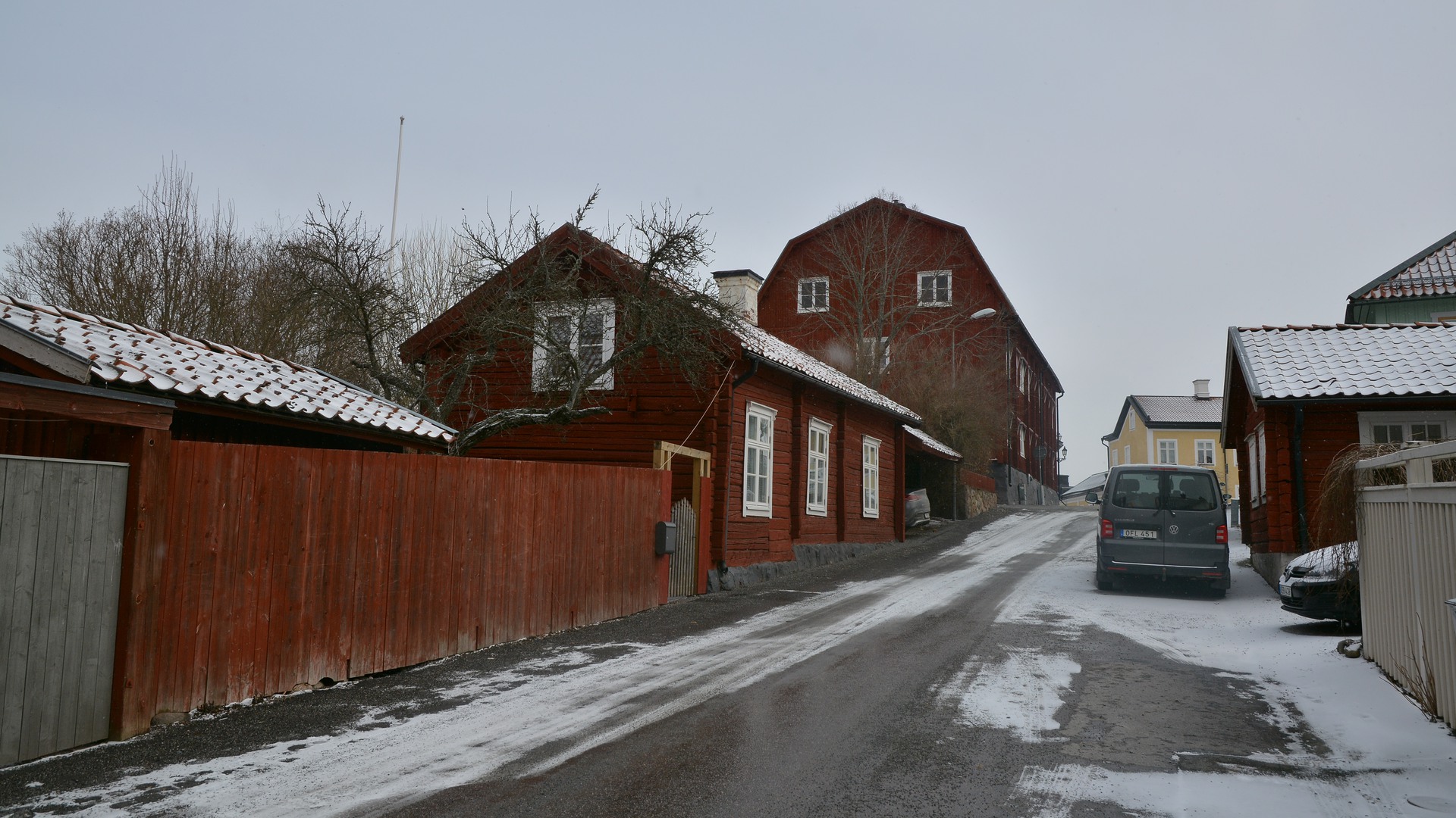 Snöig stadsgata kantade av röda gatuhus av trä. 
