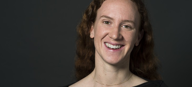 En kvinna med rött hår ler mot kameran