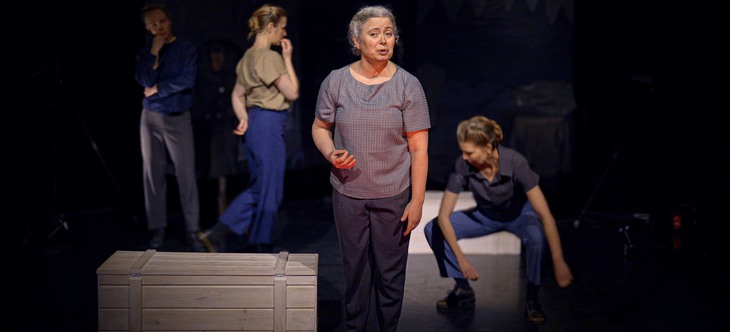 En kvinnlig skådespelare står på en scen, framför tre andra - en man och två kvinnor.