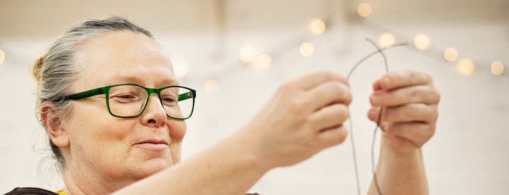 Närbild på händer som arbetar med tenntråd.