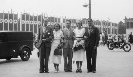 Stina med sällskap framför flaggor med hakkors, olympiska spelen i Berlin 1936.