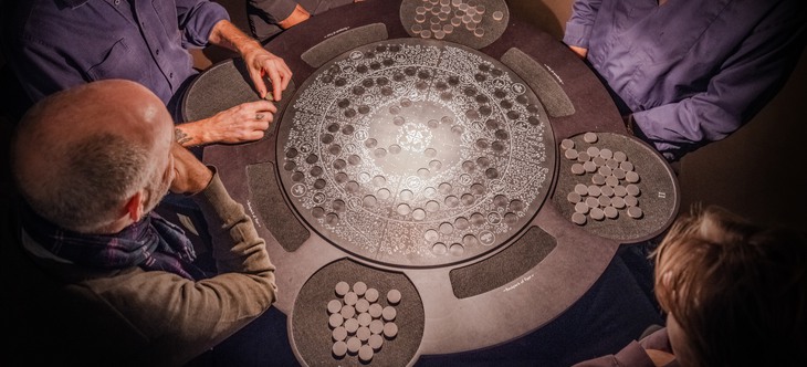 En grupp människor samlade runt ett bord med ett brädspel på. 