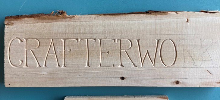 Texten Crafterwork utskuren i vedträ.