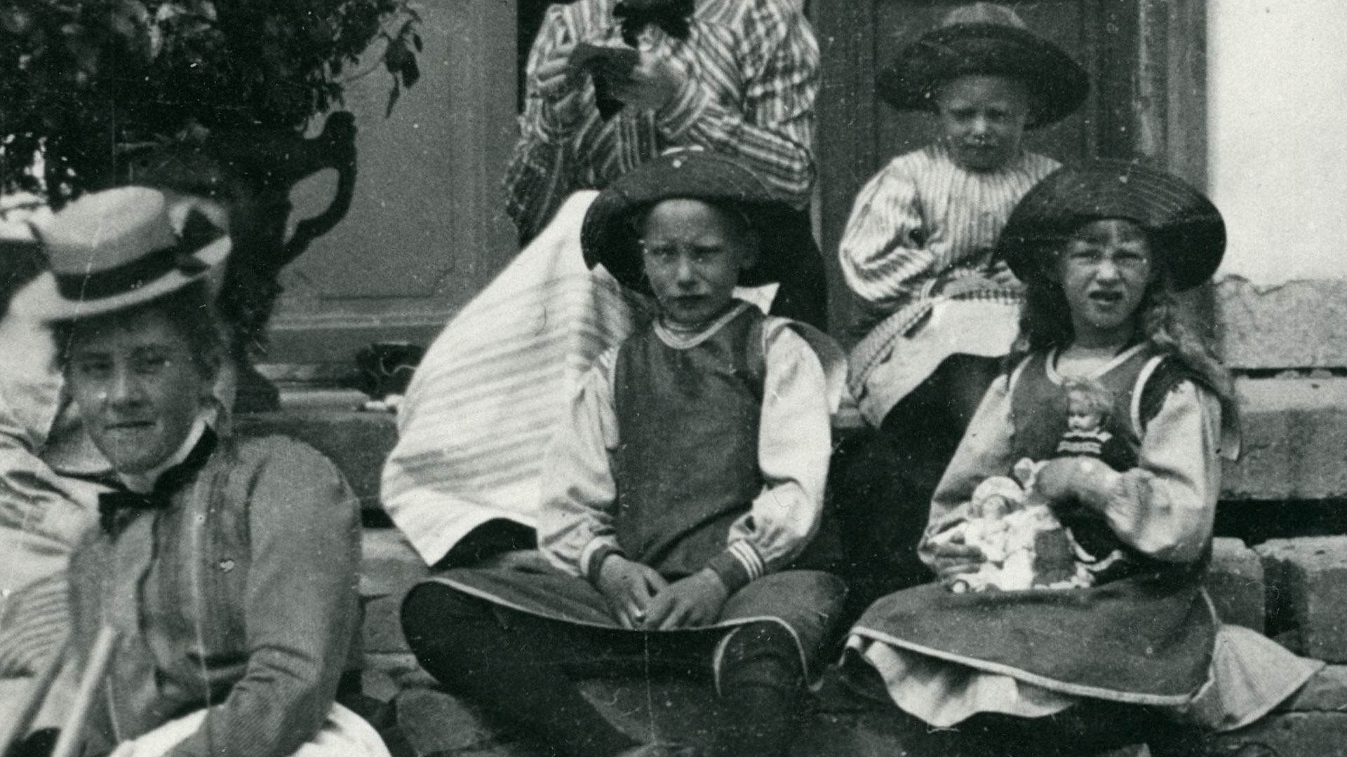 Svartvit bild, fyra barn med hattar i en trappa.