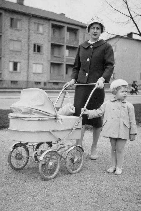 En kvinna med barnvagn, ett barn står jämte.