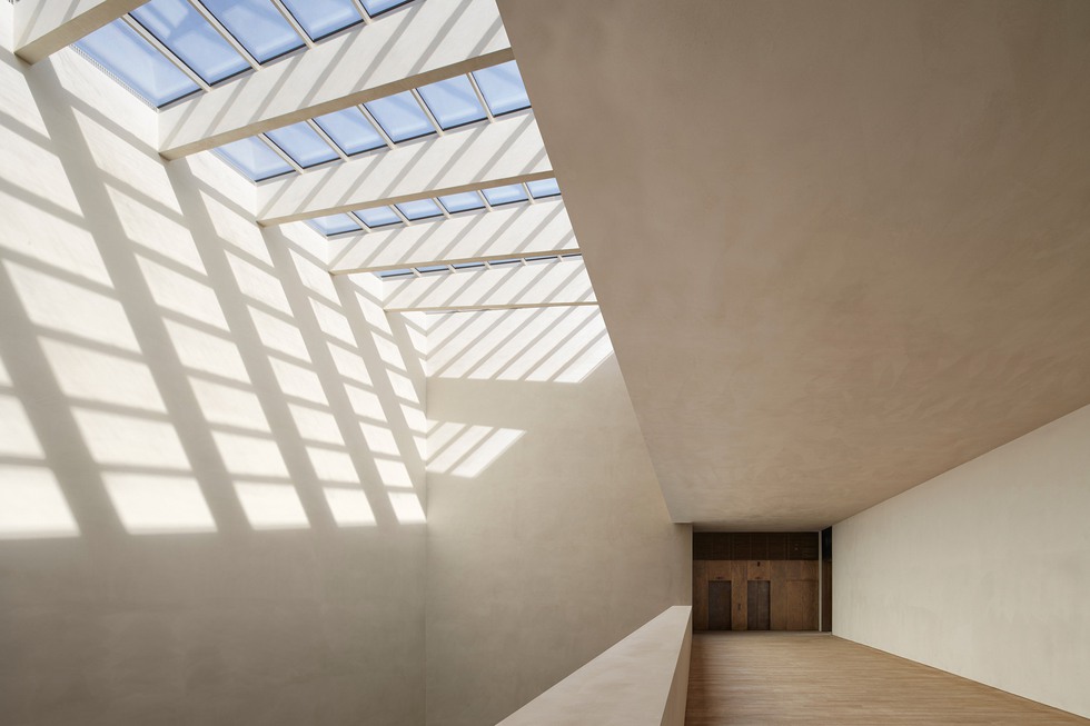 En modern museibyggnad mede stora takfönster som är lerklinad.