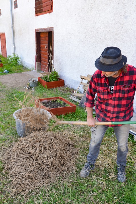 En man blandar halm med lera.