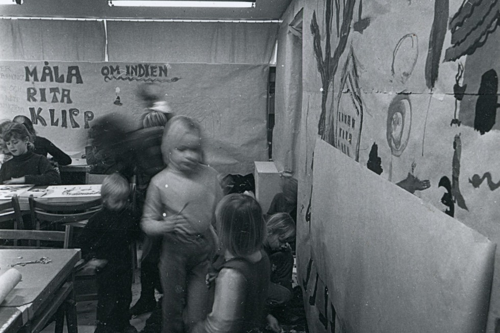Barn målar i ett rum, deras stora målningar har hängts upp på väggarna runt omkring.