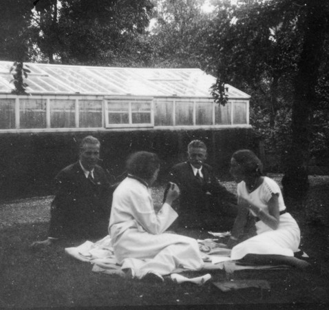 Fyra personer sitter på en filt i gräset