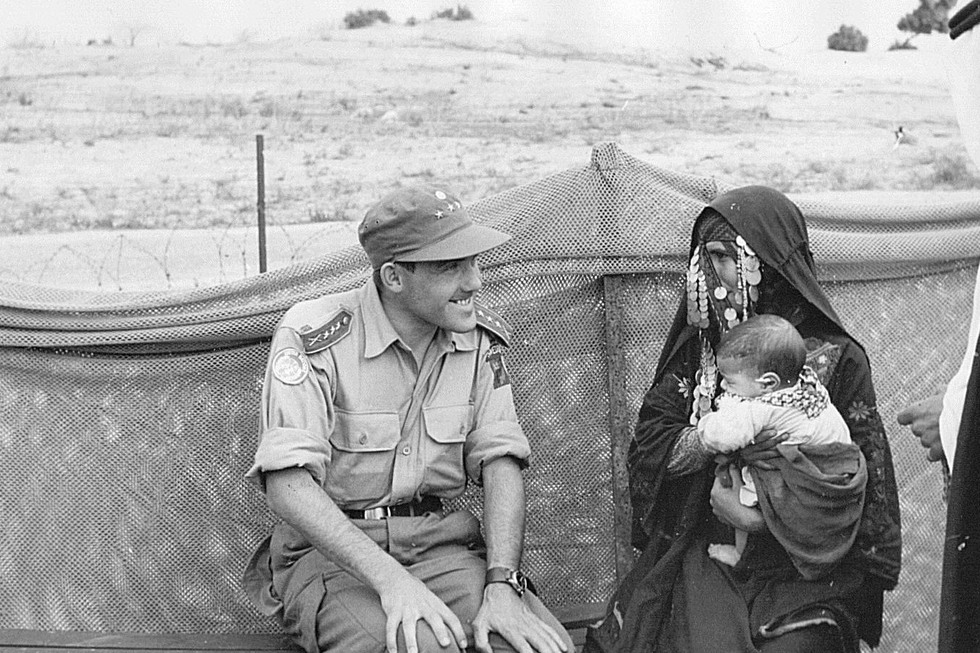 En läkare från kompaniet samtalar med en beduinkvinna. Kvinnan håller en bebis i famnen
