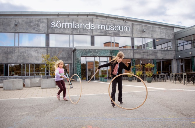 barn leker med rockringar framför Sörmlands museum