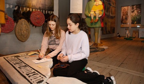 två flickor sitter på golvet i en utställning