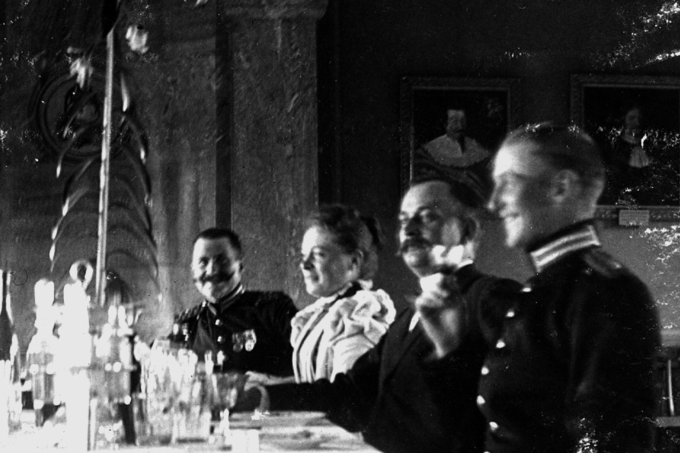 Tre soldater och en kvinna sitter vid ett dukat bord. 