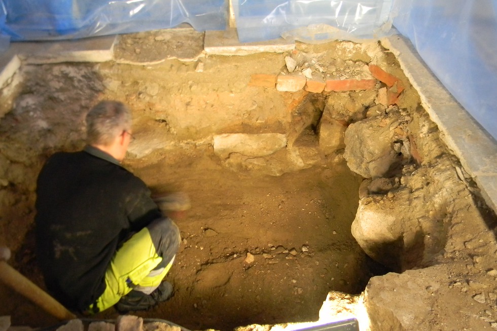 Arkeolog i en grävd grop i Överselö kyrka.