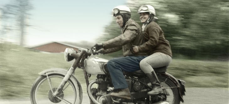 En kvinna och man med hjälmar åker på en Motorcykel.