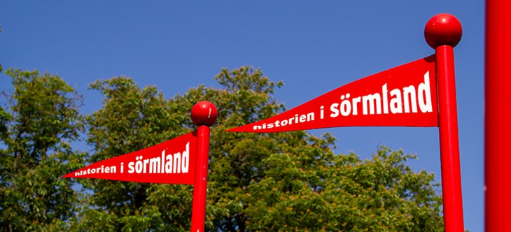 Två röda flaggor med texten Historien i Sörmland