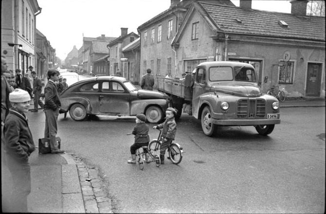en gatukorsning med bilar och små barn på cyklar