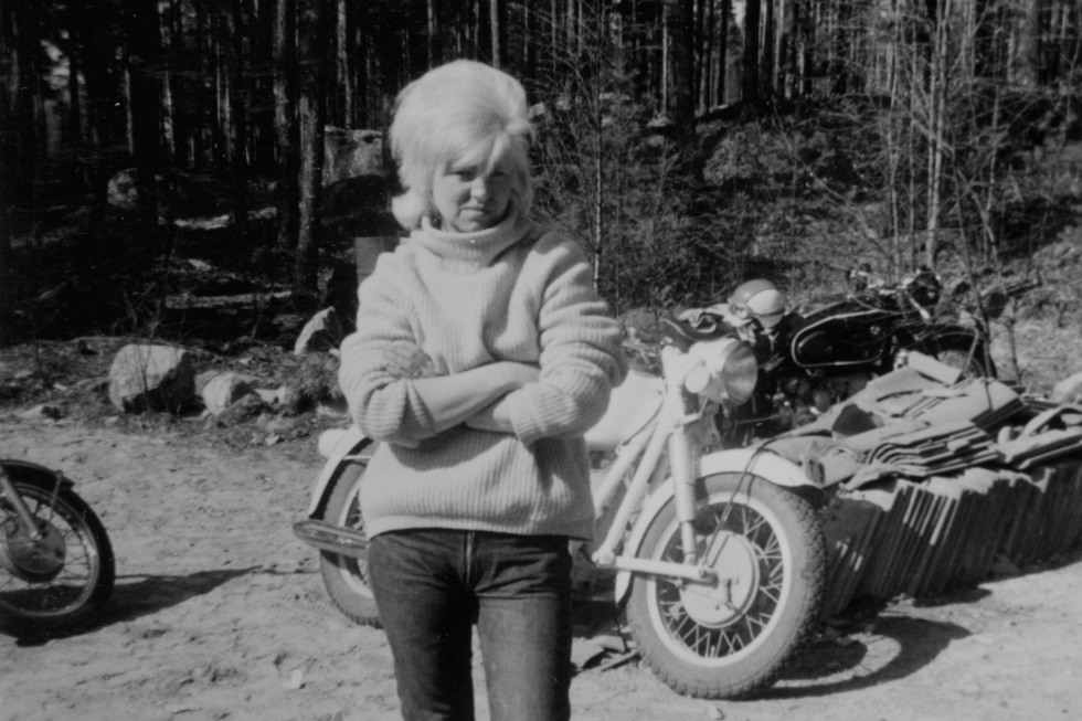 svartvit bild, ung kvinna framför motorcykel.
